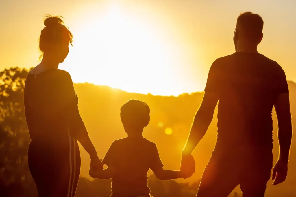 Eine Familie steht vor einem Sonnenuntergang