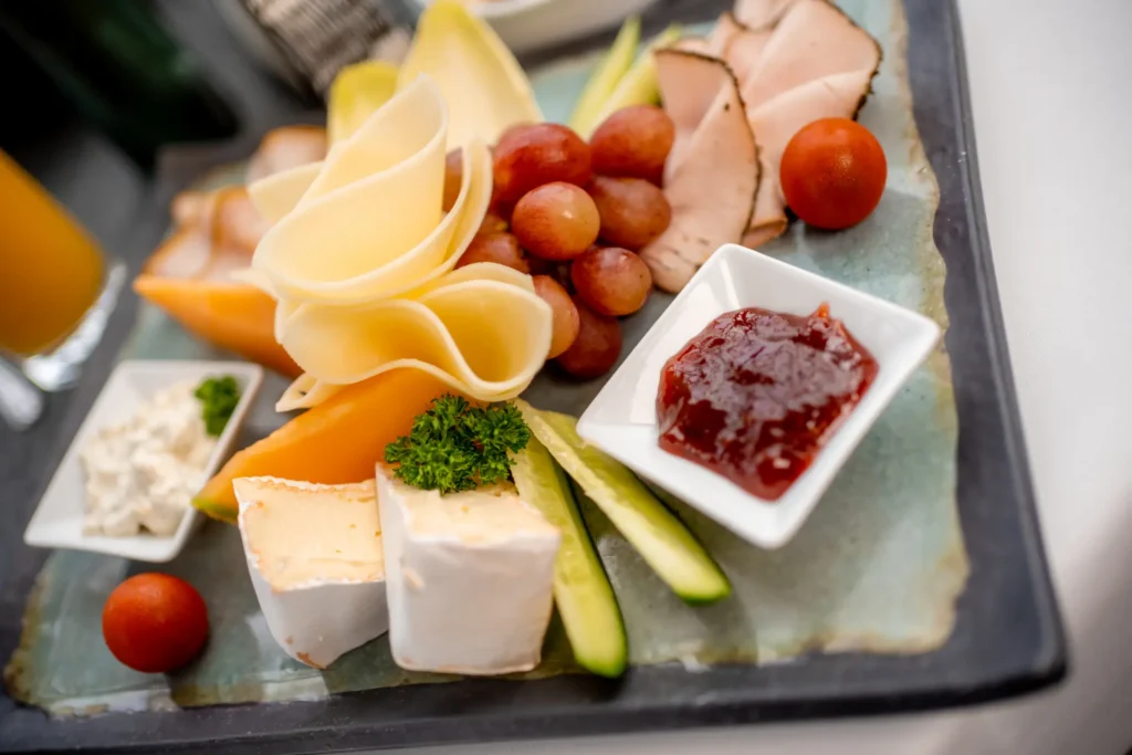 Käse, Marmelade, Gemüse und Wurst auf einem Teller angerichtet.