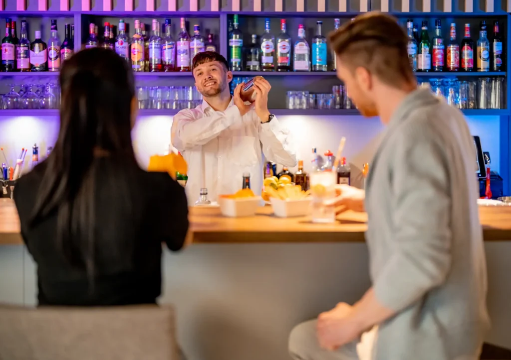 Zwei Gäste und ein Barkeeper in der Bar der Mixed Zone des K6 Seminarhotels